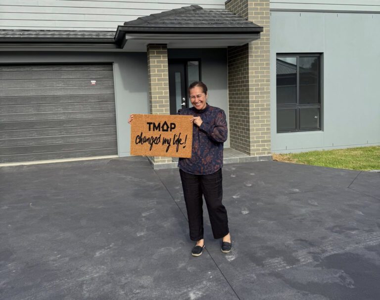 A TMAP family holding their TMAP doormat