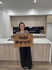 A TMAP family holding their TMAP doormat