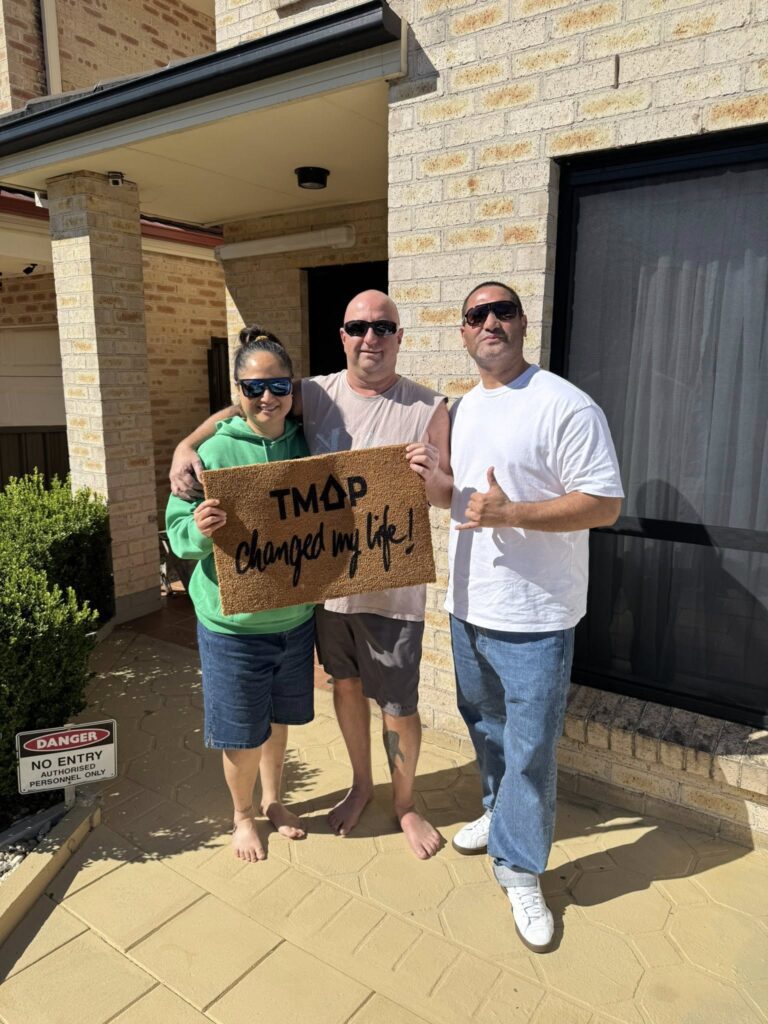 A TMAP family holding their TMAP doormat
