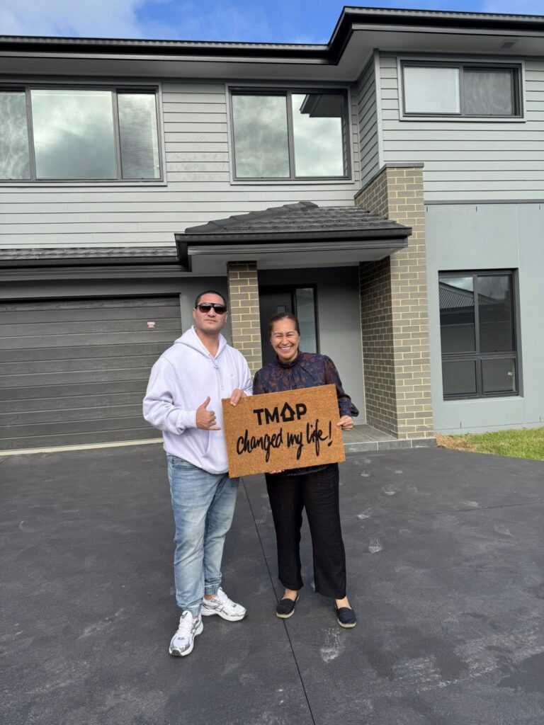 A TMAP family holding their TMAP doormat