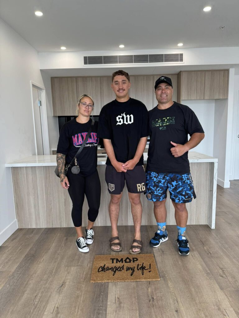 A TMAP family holding their TMAP doormat