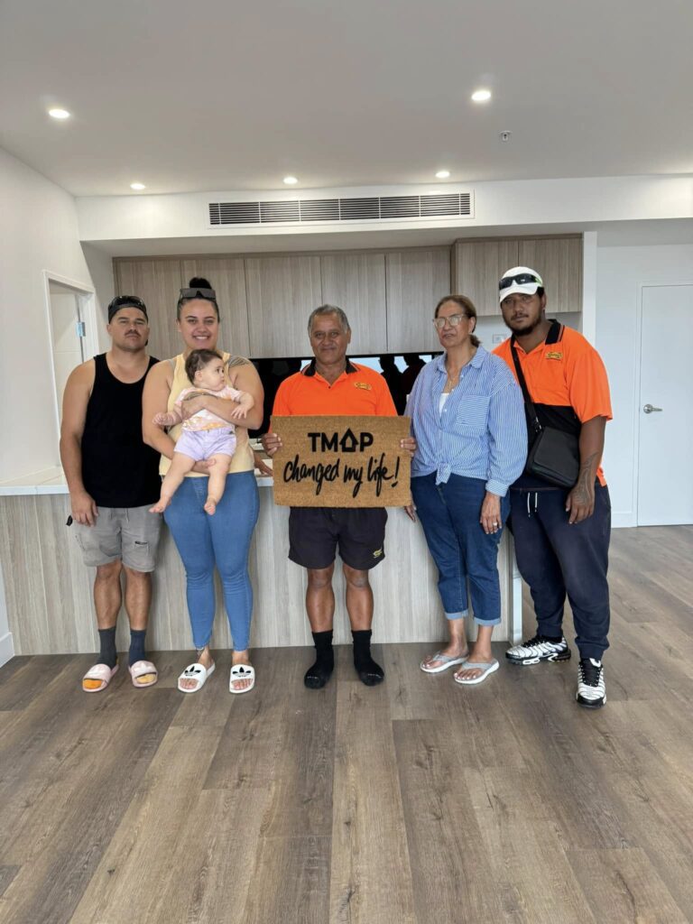 A TMAP family holding their TMAP doormat