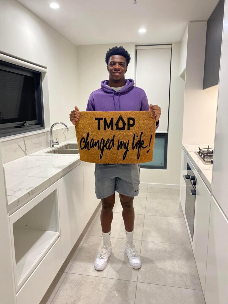 A TMAP family holding their TMAP doormat