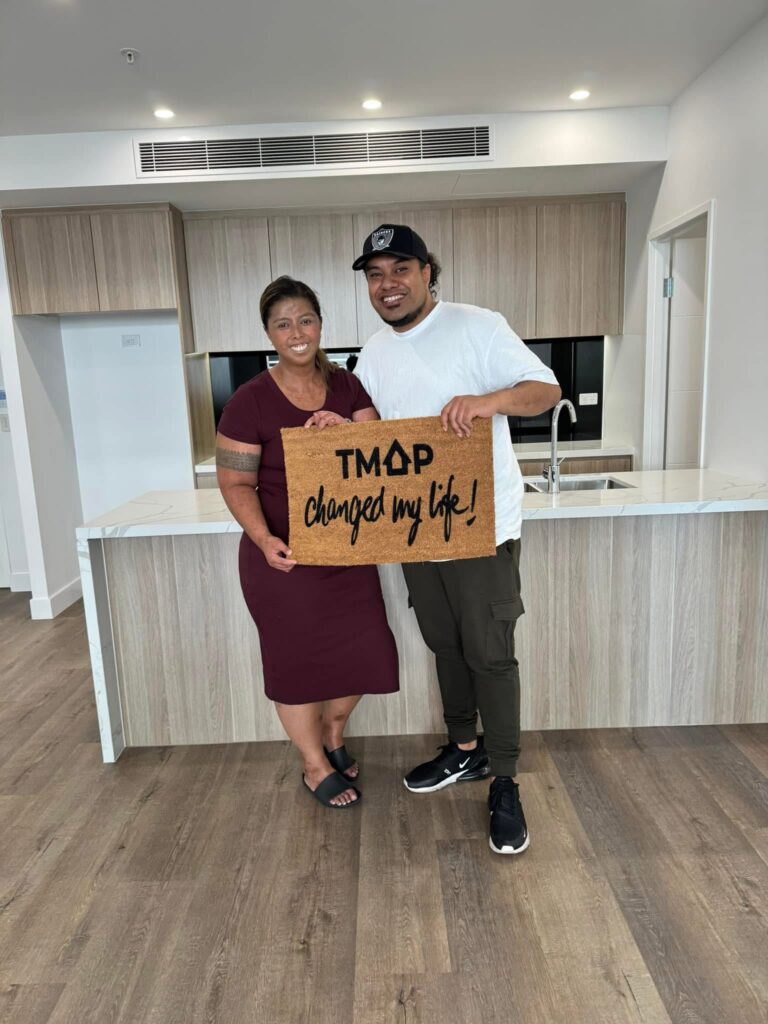 A TMAP family holding their TMAP doormat