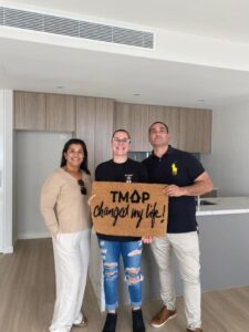 A TMAP family holding their TMAP doormat
