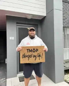 A TMAP family holding their TMAP doormat