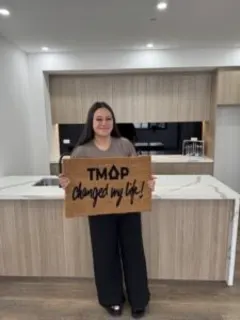 A TMAP family holding their TMAP doormat