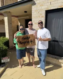 A TMAP family holding their TMAP doormat