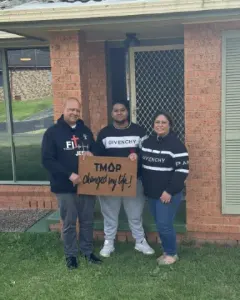 A TMAP family holding their TMAP doormat