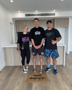 A TMAP family holding their TMAP doormat