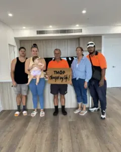 A TMAP family holding their TMAP doormat