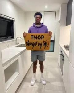 A TMAP family holding their TMAP doormat