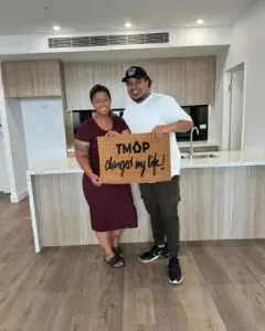 A TMAP family holding their TMAP doormat