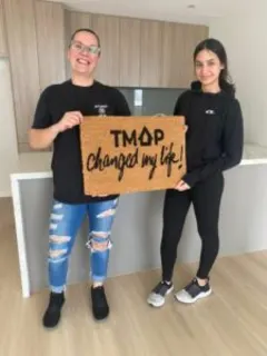 A TMAP family holding their TMAP doormat