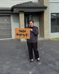 A TMAP family holding their TMAP doormat